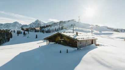 Verschneite Hütte in Bergen mit Skilift bei Sonnenschein