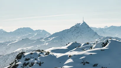 Verschneite Bergspitzen unter klarem Himmel mit Sendemast