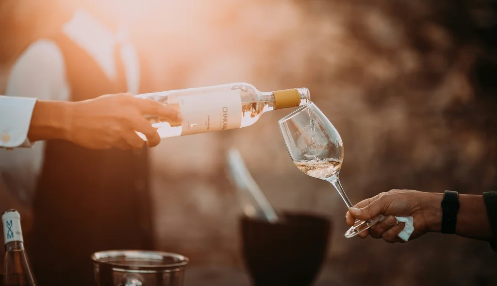 Wein wird von einer Person in ein Glas eingeschenkt