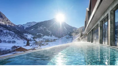 Infinity-Pool mit Blick auf schneebedeckte Berge und sonnigen Himmel