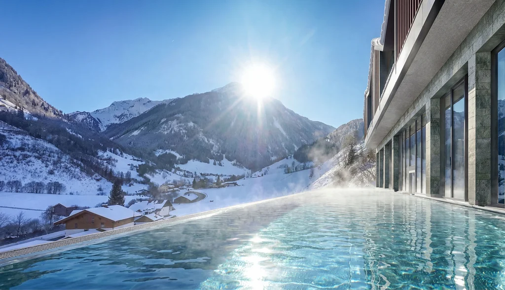 Infinity pool overlooking snowy mountains under a bright sunlit sky
