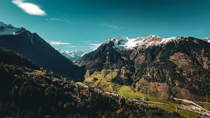 Bergtal mit schneebedeckten Gipfeln und grünem Talboden bei klarem Himmel